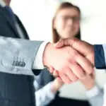 close up of two professionals with suits shaking hands