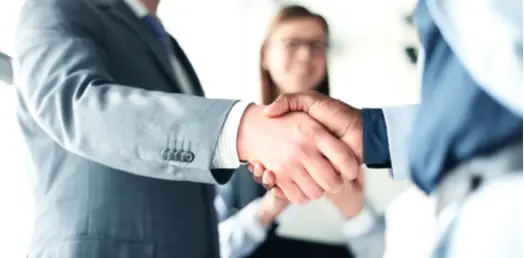 close up of two professionals with suits shaking hands