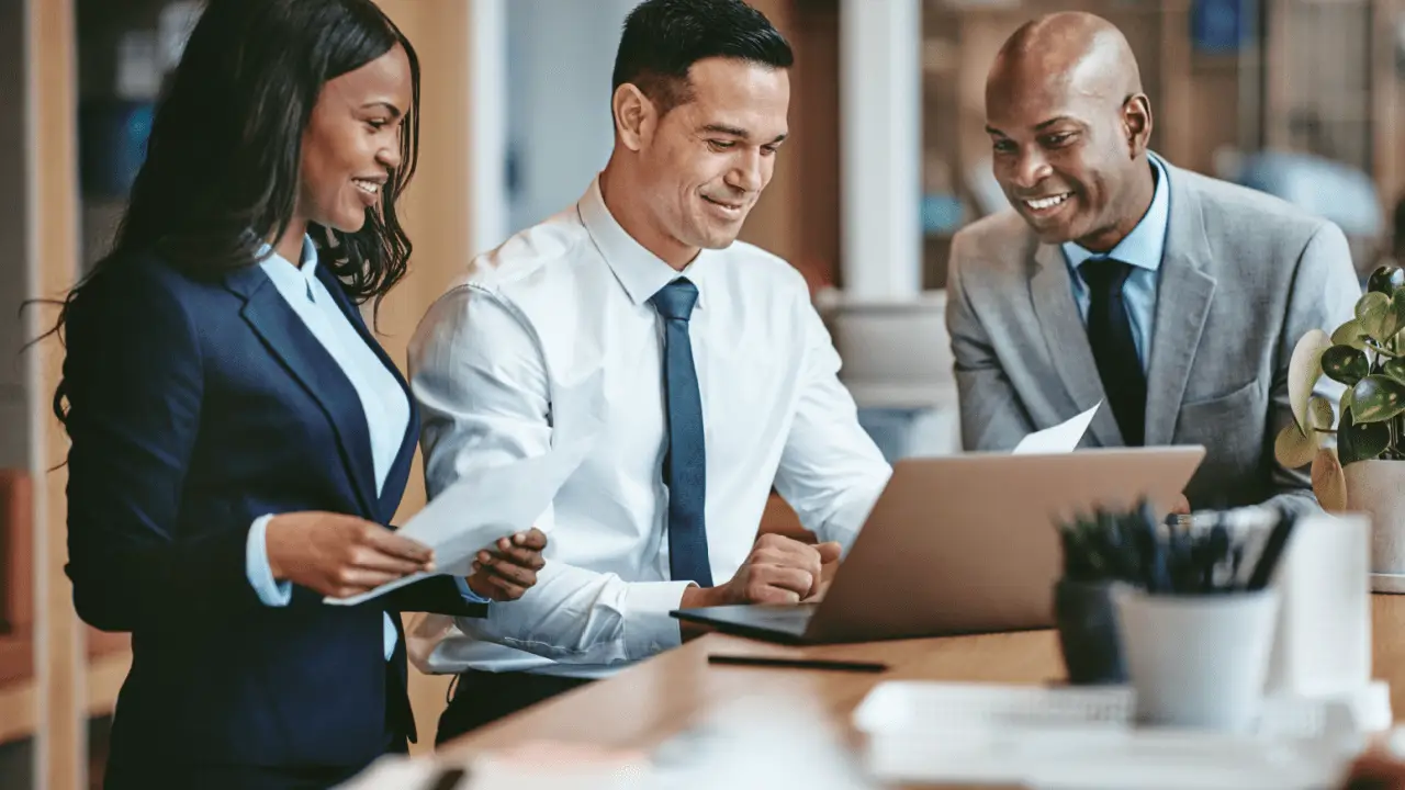 Three legal professionals reviewing client outreach strategies on a laptop — how do I get criminal defense clients?