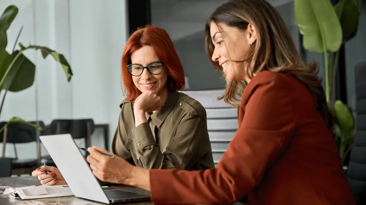 Two professional women discussing how to optimize your law firm for local SEO strategies in a modern office setting